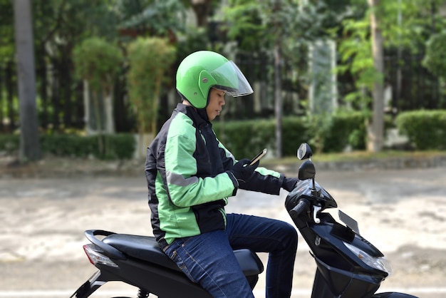 Side view of asian motorcycle taxi man checking the phone