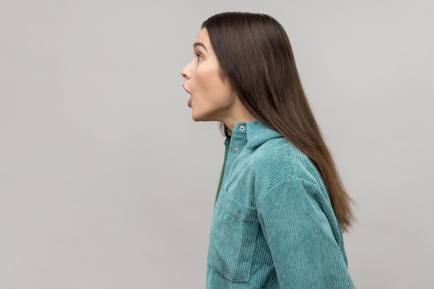 Side view of astonished woman with widely open mouth in\
amazement and big eyes looking ahead