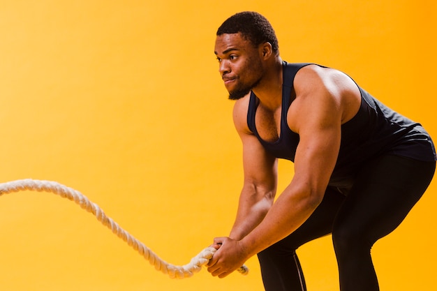 Photo side view of athletic man with rope and copy space