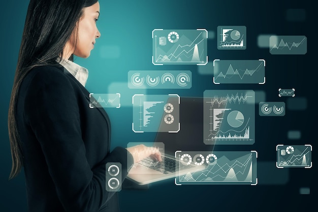 Side view of attractive busiesswoman typing on laptop keyboard with abstract glowing business chart and graph hologram on blurry blue background Technology and finance concept Double exposure