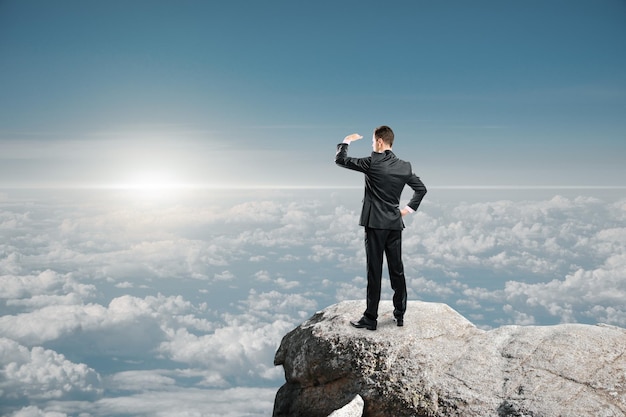 Side view of attractive young caucasian businessman standing on cliff