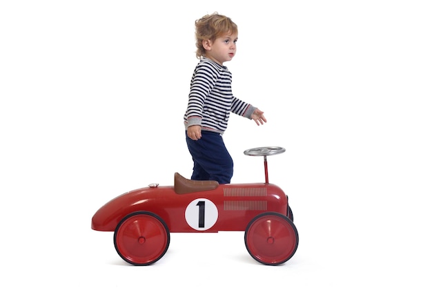 Side view of a baby boy playing with car toy the baby boy standing on white background