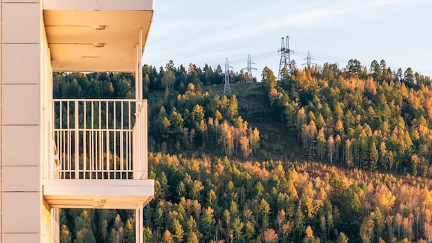 Side view of the balcony of an apartment building against the backdrop of a mountain in the rays of the setting sun