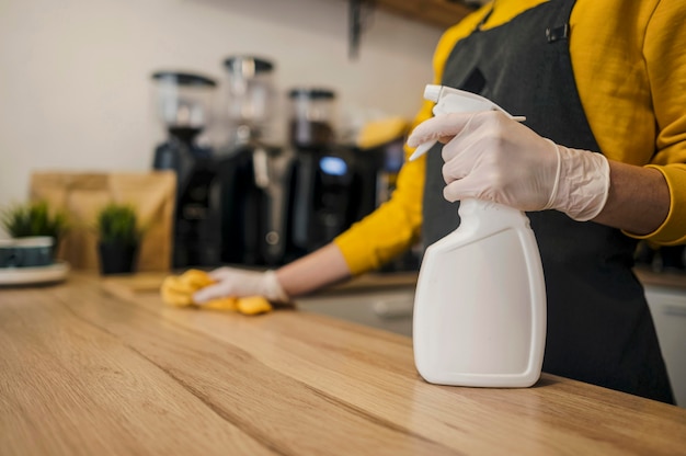 Photo side view of barista cleaning surface