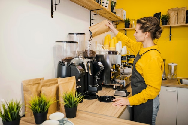 Photo side view of barista grinding coffee