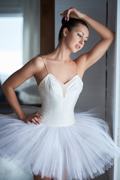 Side view of beautiful ballerina standing and looking through window. Copyspace