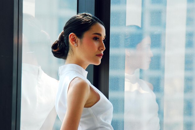 side view of beautiful businesswoman looking away while standing by window in office