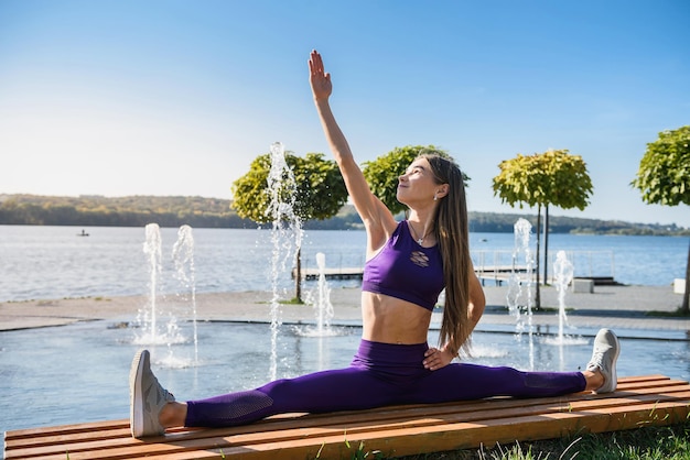 Side view of a beautiful european  young woman athlete doing the splits while sitting on a warm summer day. sport active lifestyle concept.