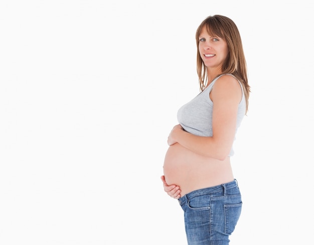 Вид сбоку красивая беременная женщина, лаская ее живот, стоя
