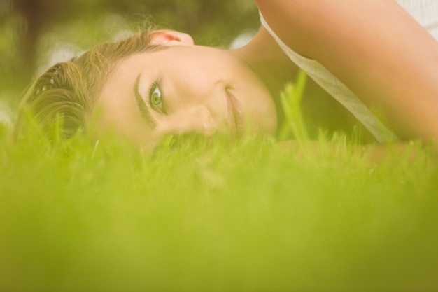 Foto vista laterale di bella donna sorridente che si trova sull'erba