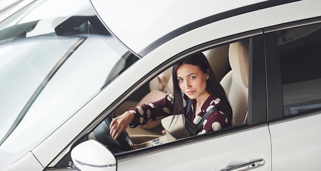 Side view of beautiful young brunette that inside of modern automobile Riding car