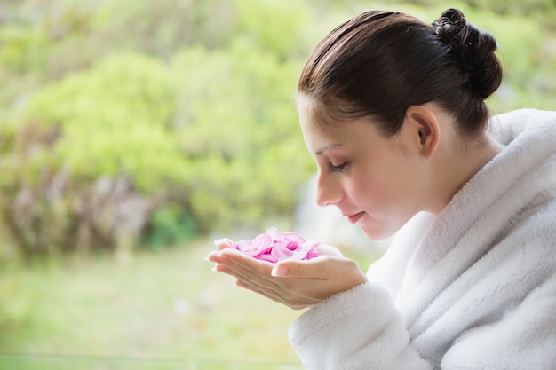 Vista laterale dei fiori sententi l'odore della bella giovane donna