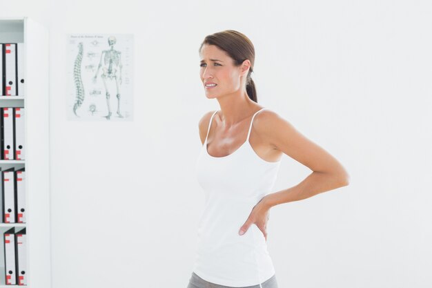 Side view of a beautiful young woman with back pain