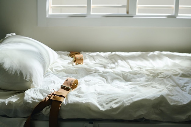 Side view of bed for insane patient standing by window in mental hospital ward