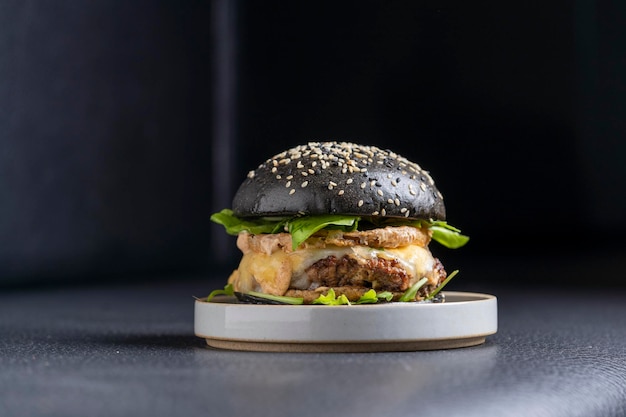 Side view of a black beef burger in a large plate on the ground.