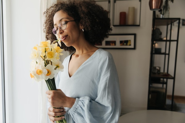 Photo side view of black smiling woman smell flowers