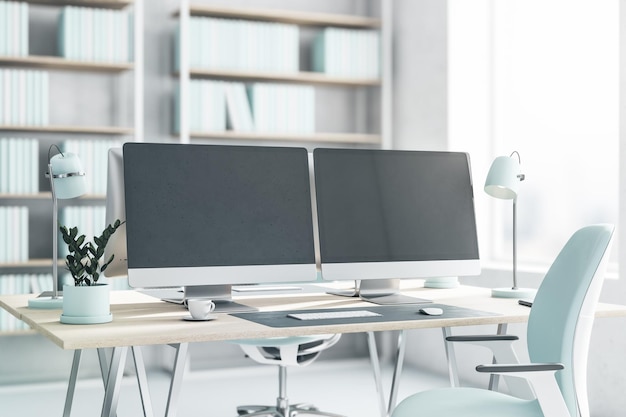 Side view on blank dark modern computer monitors on light\
wooden table with light blue lamp flowerpot and chair on white\
floor in sunny office with big window 3d rendering mockup