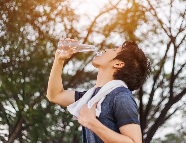 木に向かってガラスを飲んでいる少年のサイドビュー