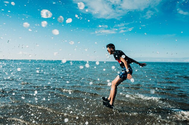 空に向かって海に飛び込んでいる男の子の横の景色