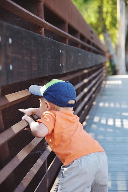 Photo side view of a boy looking through railings