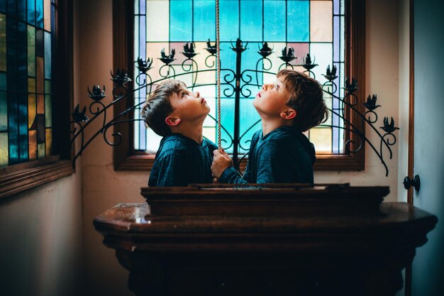 Foto vista laterale di un ragazzo che guarda attraverso la finestra a casa