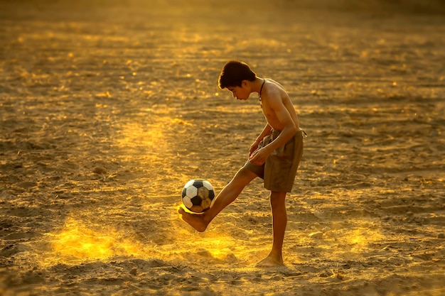 Photo side view of boy playing with ball at sunset