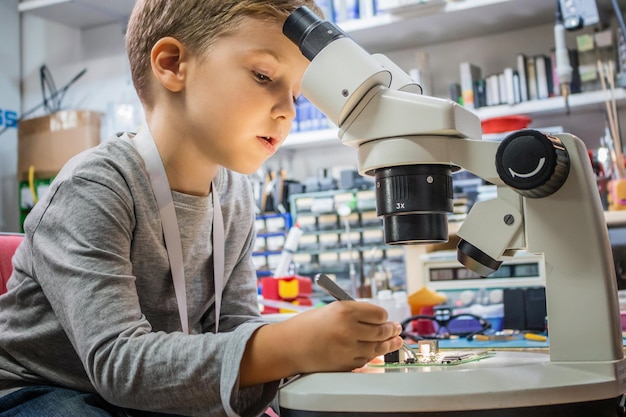 Photo side view of boy repairing computer chip on table