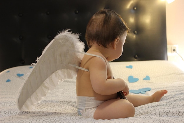 Photo side view of boy sitting on bed at home