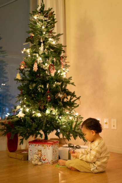 Side view of boy sitting by christmas tree on floor at home