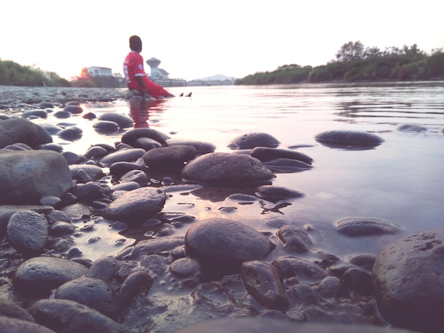 Foto vista laterale di un ragazzo seduto su ciottoli sulla spiaggia