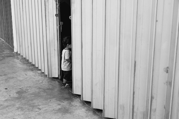 Side view of boy standing by shutter