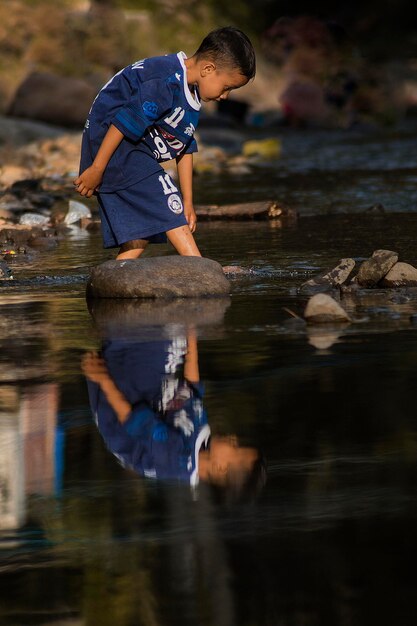 Photo side view of boy standing in lake