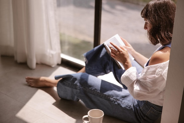 The side view brunette hair woman sitting on the floor reading book