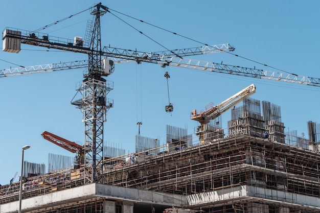 Side view of building under construction with cranes and equipment