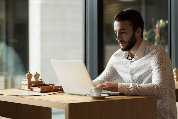 Uomo di affari di vista laterale che lavora al computer portatile