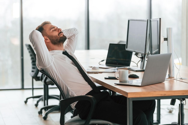 side view businessman is sitting by computer and working in the office