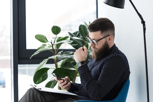 side view of businessman with notepad using smartphone