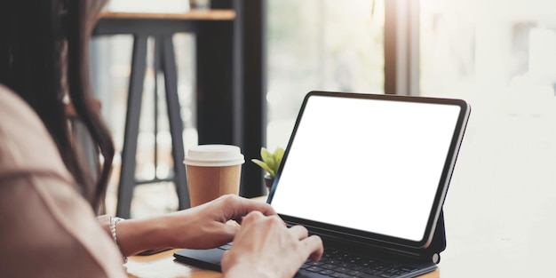 Side view of a businesswoman working on a laptop blank white screen at office Mock up