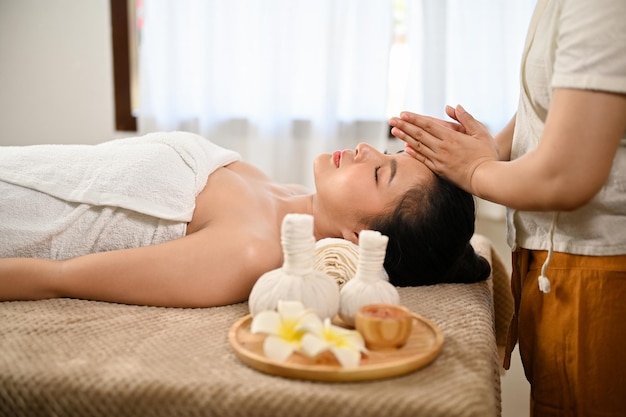 Side view Calm Asian woman lying on massage table getting massage Thai spa Thai massage