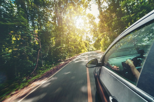 Вид сбоку вождения автомобиля по дороге в лесу шоссе