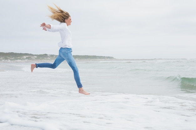 Вид сбоку случайные женщина прыгает на пляже