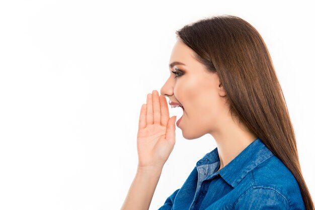 Side view of cheerful young woman holding hand near mouth and screaming