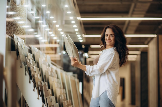 Side view of a cheerful young woman smiling while choosing new floor tiles for her home at the tile shop High quality photo