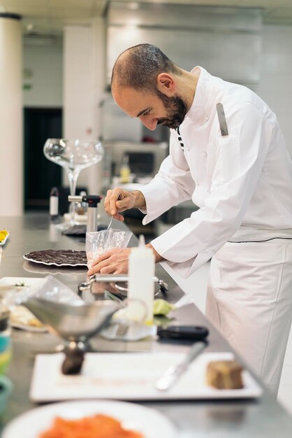 Foto vista laterale dello chef che prepara il cibo in una cucina commerciale
