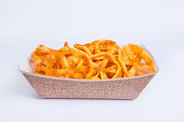 Side view of chicharrones de harina in textured tan serving boat on white background