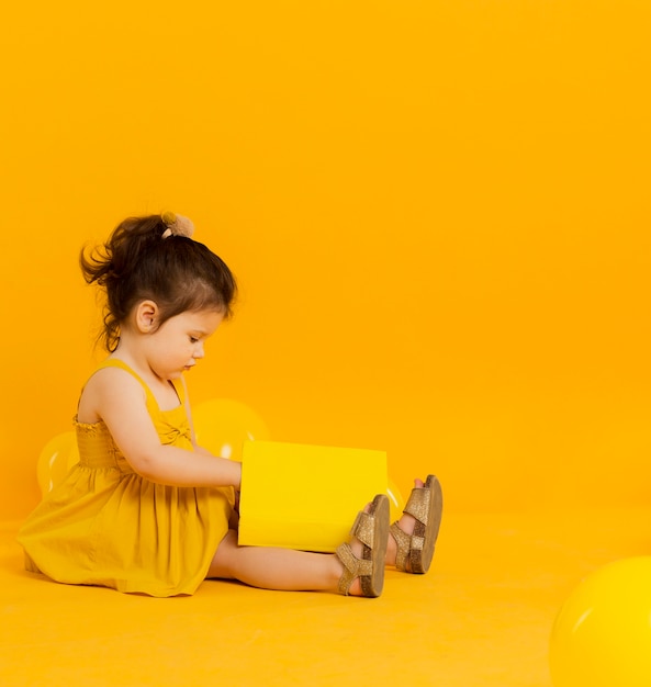 Photo side view of child posing with a book and copy space