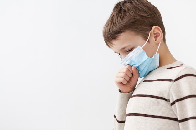 Side view of child with medical mask coughing