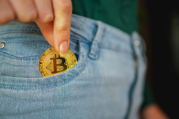 Side view close-up bitcoin golden coin inside jeans pocket.