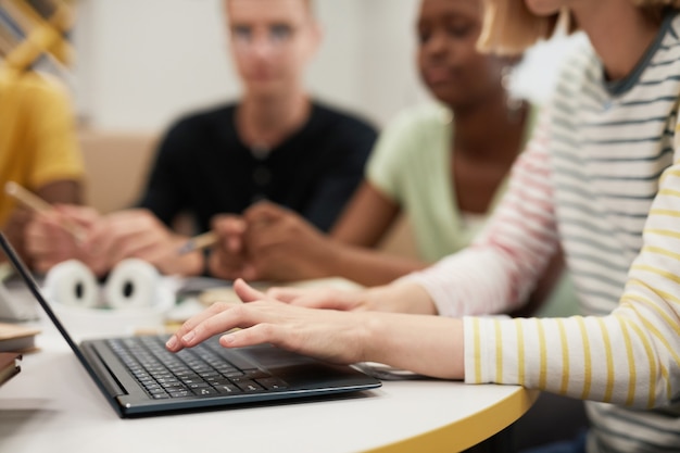 Photo side view close up at diverse group of young people studying together at table in college library fo...