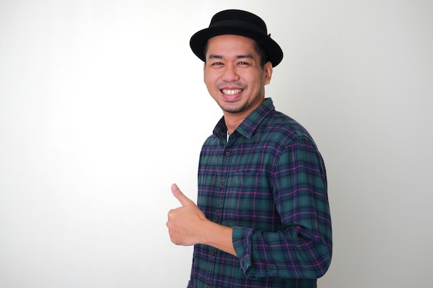 Photo side view of cool asian man smiling happy while giving thumb up